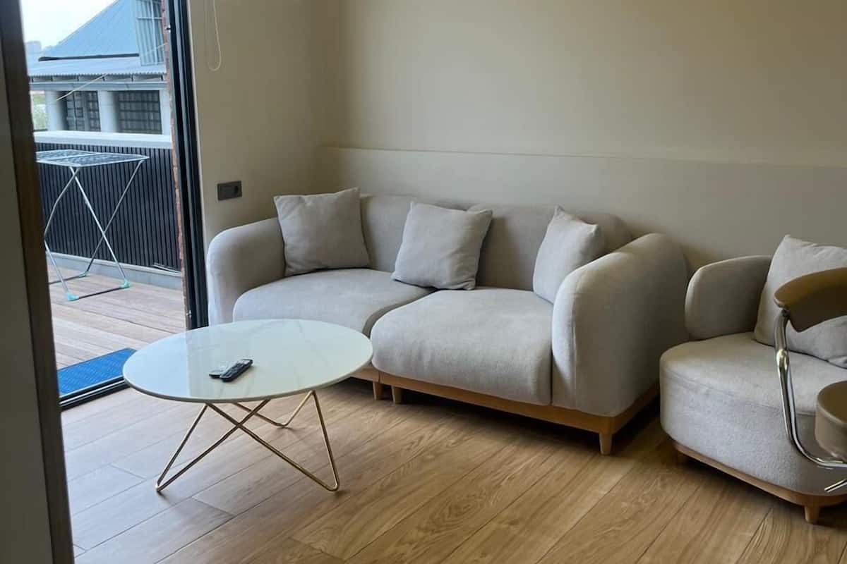 A modern living room with a light-colored sofa, a round coffee table, and a unique ceiling light fixture.