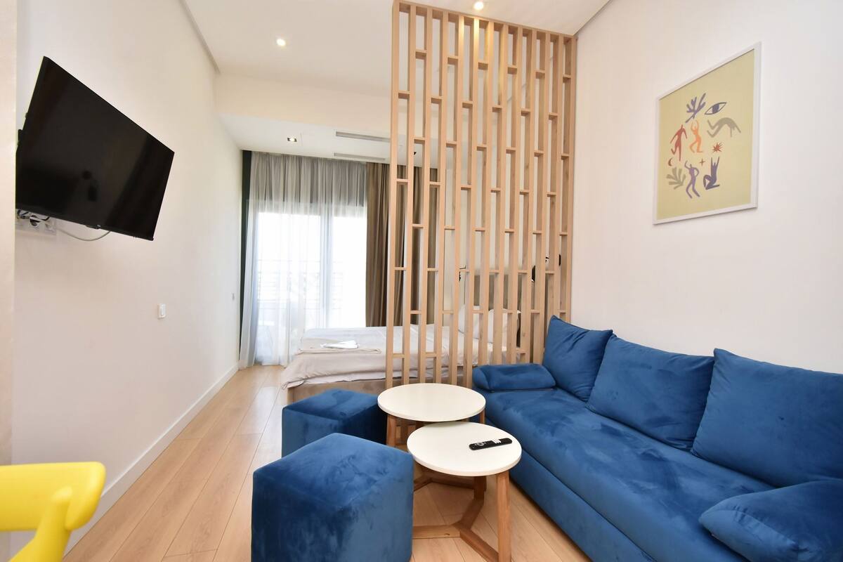 A modern living room with a blue sofa, a small round table, and a yellow chair.