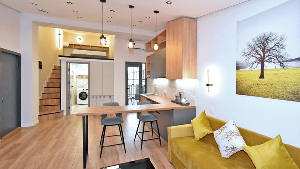 Una cocina moderna con una isla central, armarios de madera e iluminación colgante.