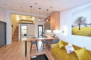 A modern kitchen with a central island, wooden cabinets, and pendant lighting.
