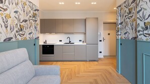 Una cocina moderna con gabinetes grises, un lavamanos negro y un suelo de madera en espiga.
