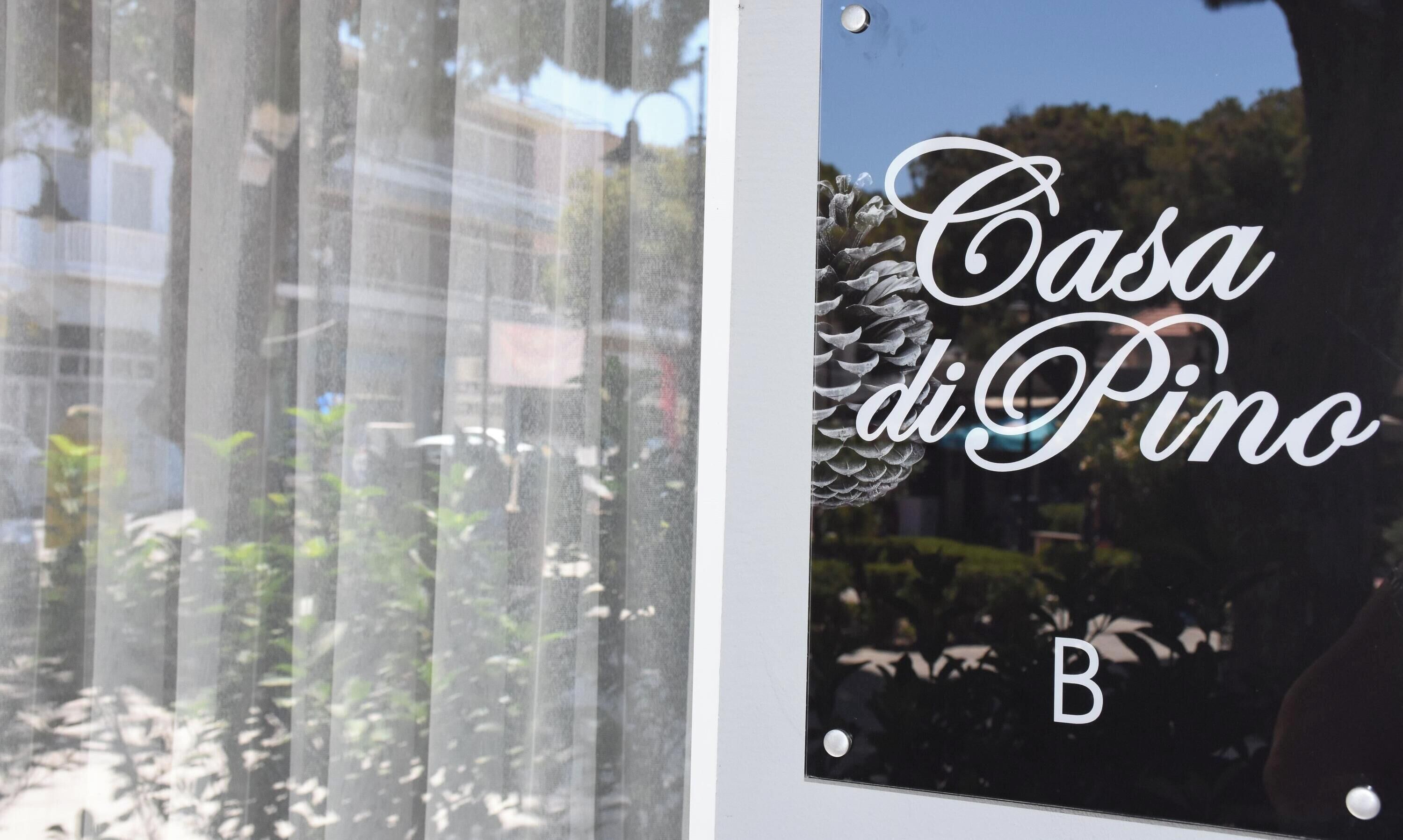 Finestra amb la inscripció 'Casa di Pino' i un pi decoratiu.