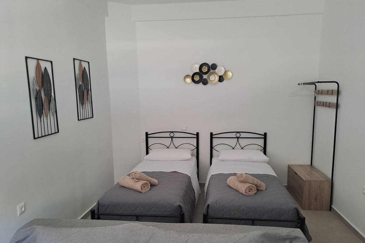Een slaapkamer met twee enkele bedden, een nachtkastje, een wandlamp en een lijst met een kunstwerk aan de muur.