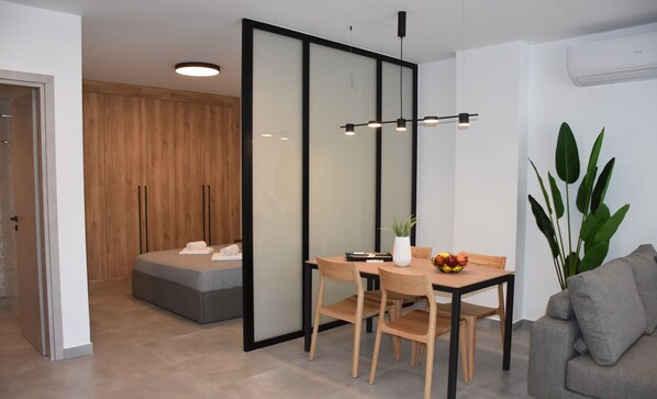 A modern room with a dining table, chairs, a potted plant, and a sofa. - Casa di Pino in Paradisi Square Near Airport (Rhodes)