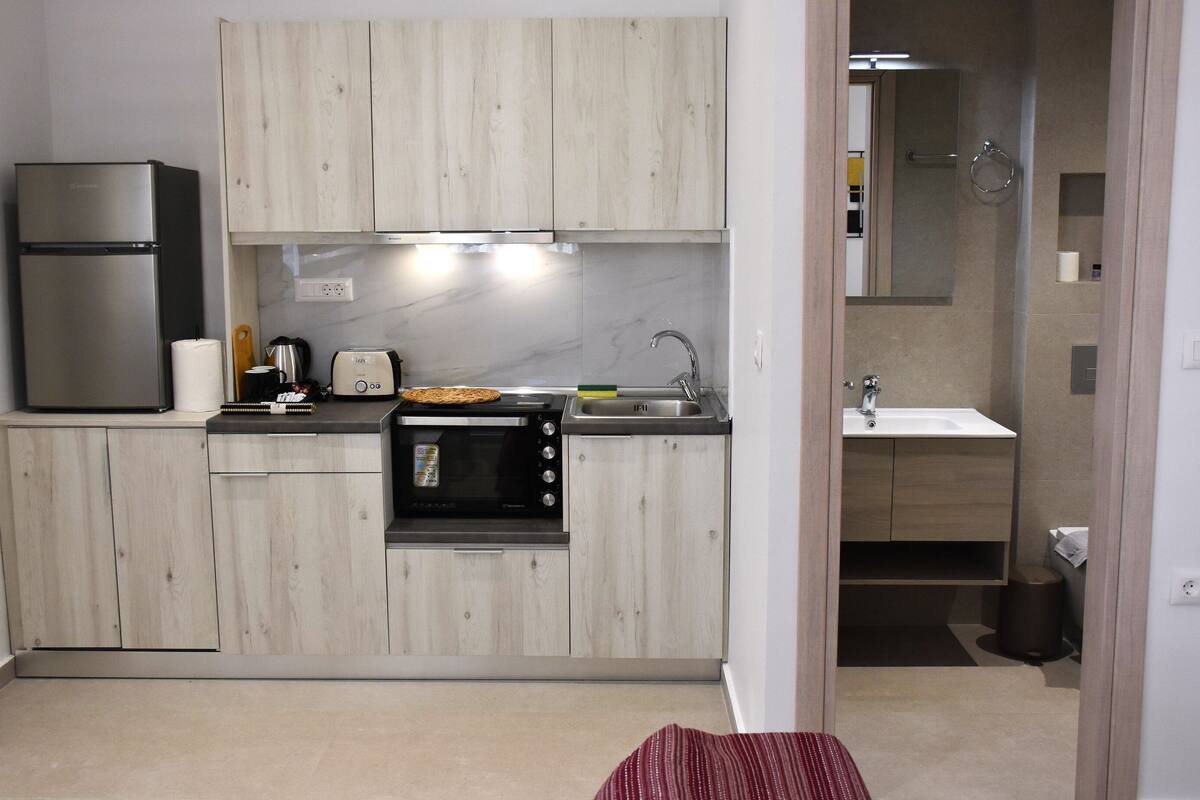 Een kleine keuken met een koelkast, broodrooster, oven en gootsteen.