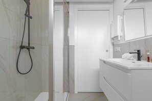 Deluxe appartement | Badkamer | Een douche, een haardroger, handdoeken, zeep