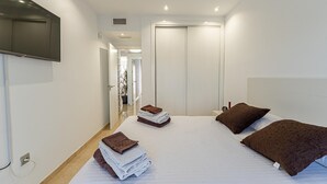 Une chambre d’hôtel avec un grand lit, un téléviseur fixé au mur et une porte donnant sur un couloir.