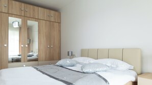 Una camera da letto con un letto, un armadio, un comodino e uno specchio.