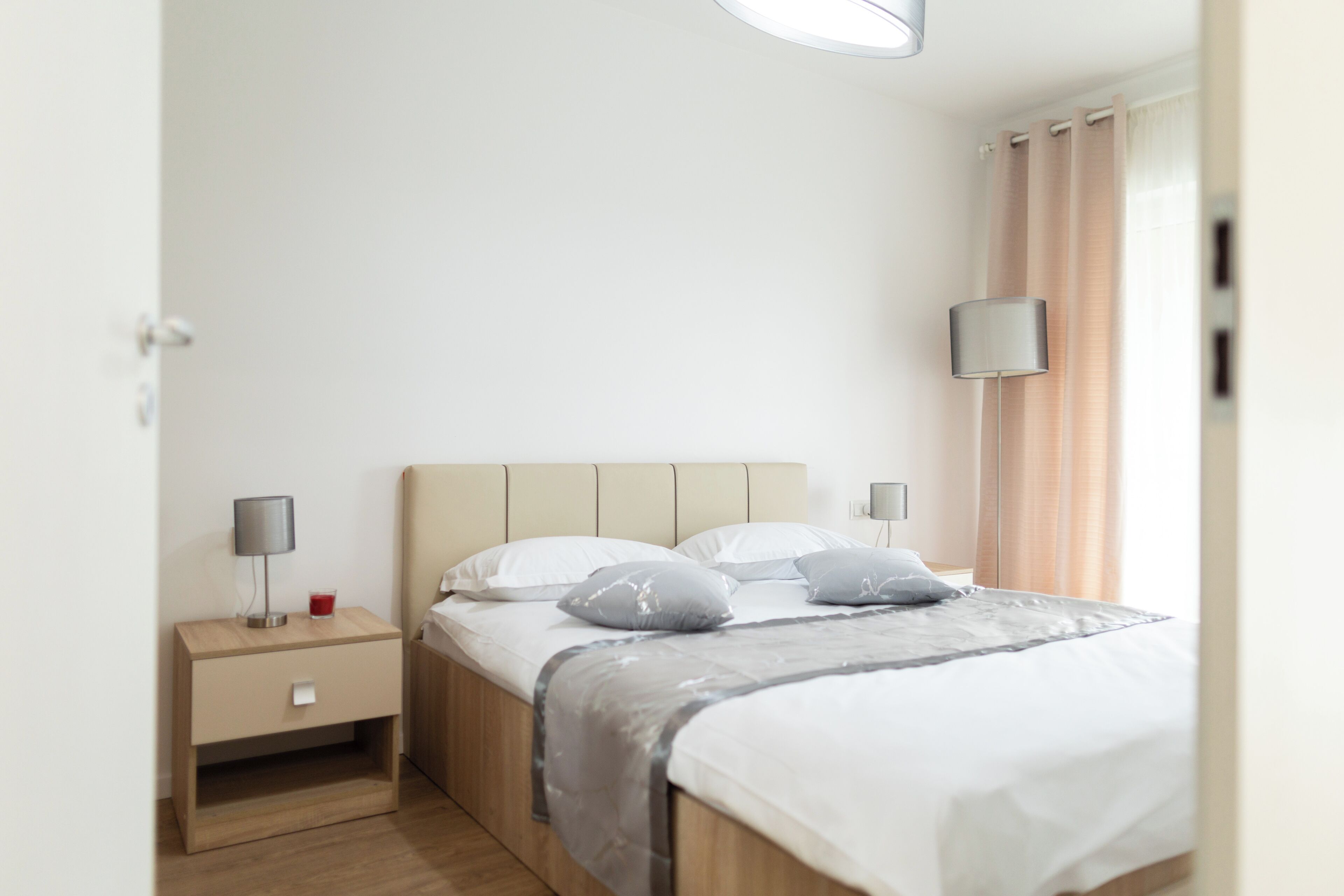 A neatly arranged bedroom with a bed, bedside tables, and a lamp.