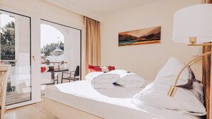 A hotel room with a bed, a desk, and a view through a glass door. - Schlosshotel Seewirt (Stadl-Predlitz)
