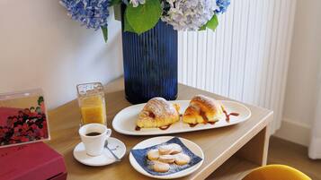 A dining table with a vase of flowers, plates of food, a cup of coffee, and a red box.