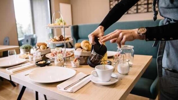 A breakfast setup with a coffee pot, cups, and a tiered dessert stand. - Hotel Ristorante Valamerica (Sernio)