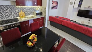 A modern kitchen with a black countertop, red cabinets, and a fruit bowl. - Modern Apartment Nikola in a Quiet Area (Kastela)