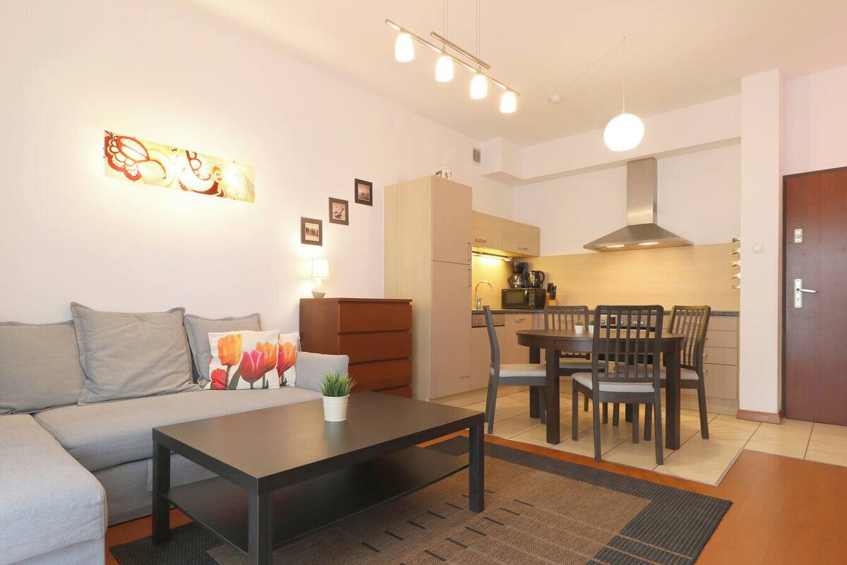 A modern living room with a sofa, coffee table, and dining area.
