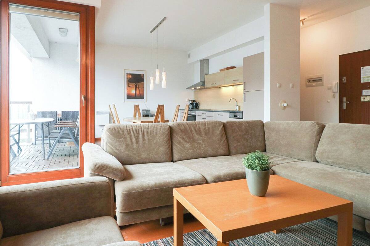 A modern living room with a beige sectional sofa, a wooden coffee table, and a view of the outdoor patio area.