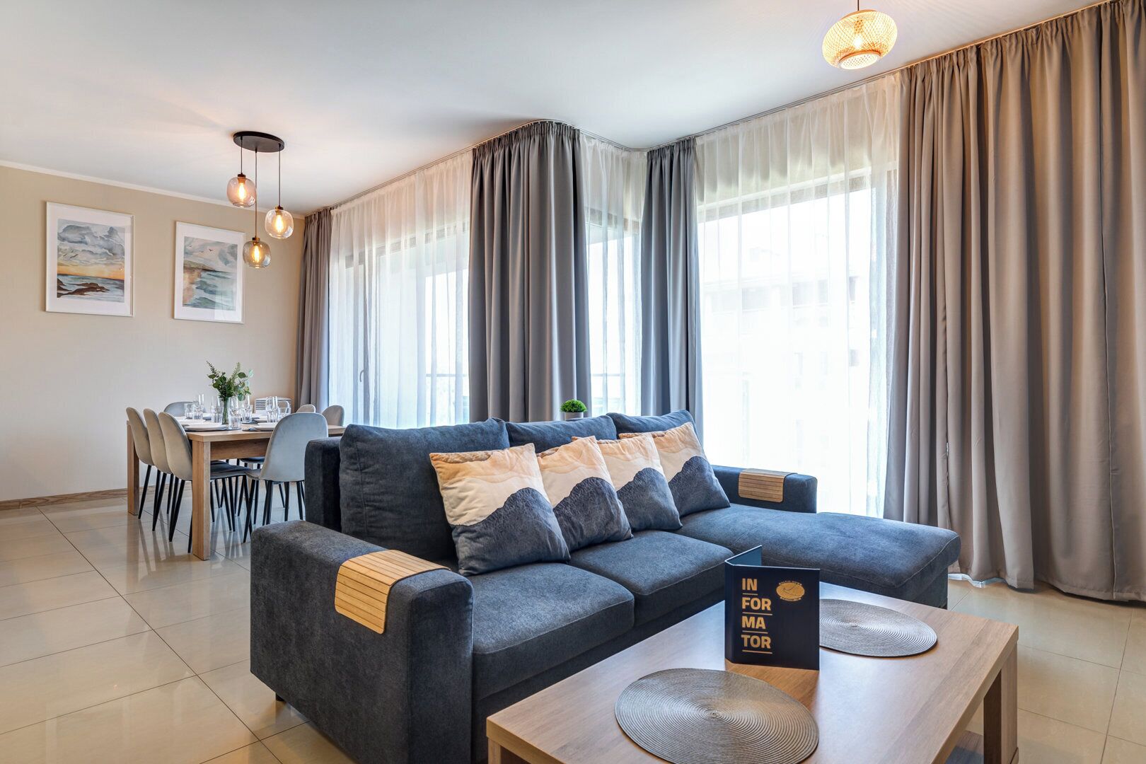 Una sala de estar moderna con un sofá gris, una mesa de centro de madera y un comedor con mesa y sillas.