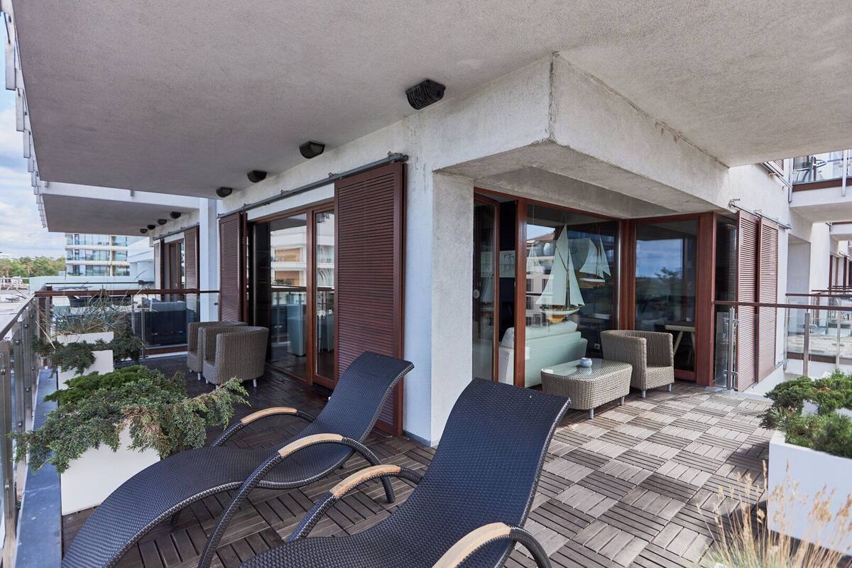 A balcony with wicker chairs, a table, and a sailboat decoration.