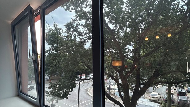 A window with a view of a street and trees.