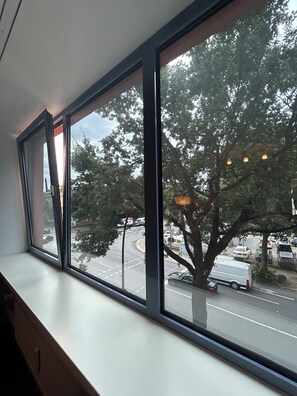 A window with a view of a street and trees. - Apartments am Südkanal (Hamburg)