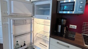 A compact kitchen with a built-in refrigerator, a microwave, and a coffee maker.