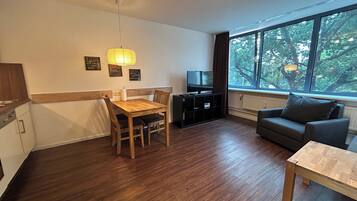 Una sala moderna con una mesa de comedor de madera, un sofá y una televisión.