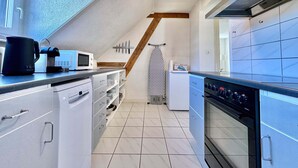 Eine moderne Küche mit weißen Schränken, einem eingebauten Backofen und einer Mikrowelle.