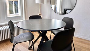 Ein Zimmer mit einem runden Tisch, vier Stühlen, einer Lampe und einem Spiegel an der Wand.