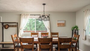 Een eethoek met een houten tafel en stoelen, een hanglamp en een raam met gordijnen.