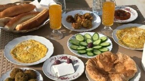 A table with various dishes including bread, eggs, and meatballs, along with drinks and water bottles. - Pyramids Kingdom  (Giza)