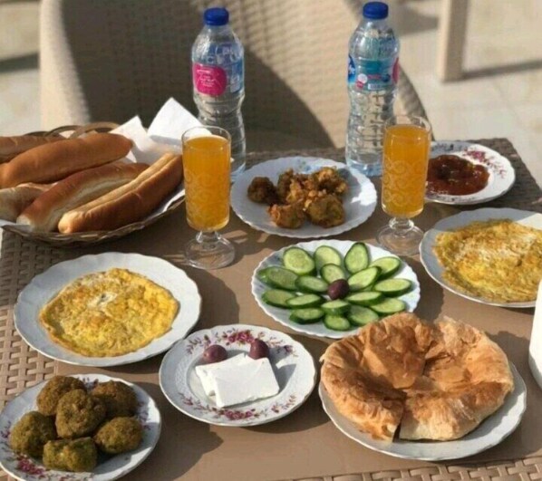 A table with various dishes including bread, eggs, and meatballs, along with drinks and water bottles. - Pyramids Kingdom (Giza)
