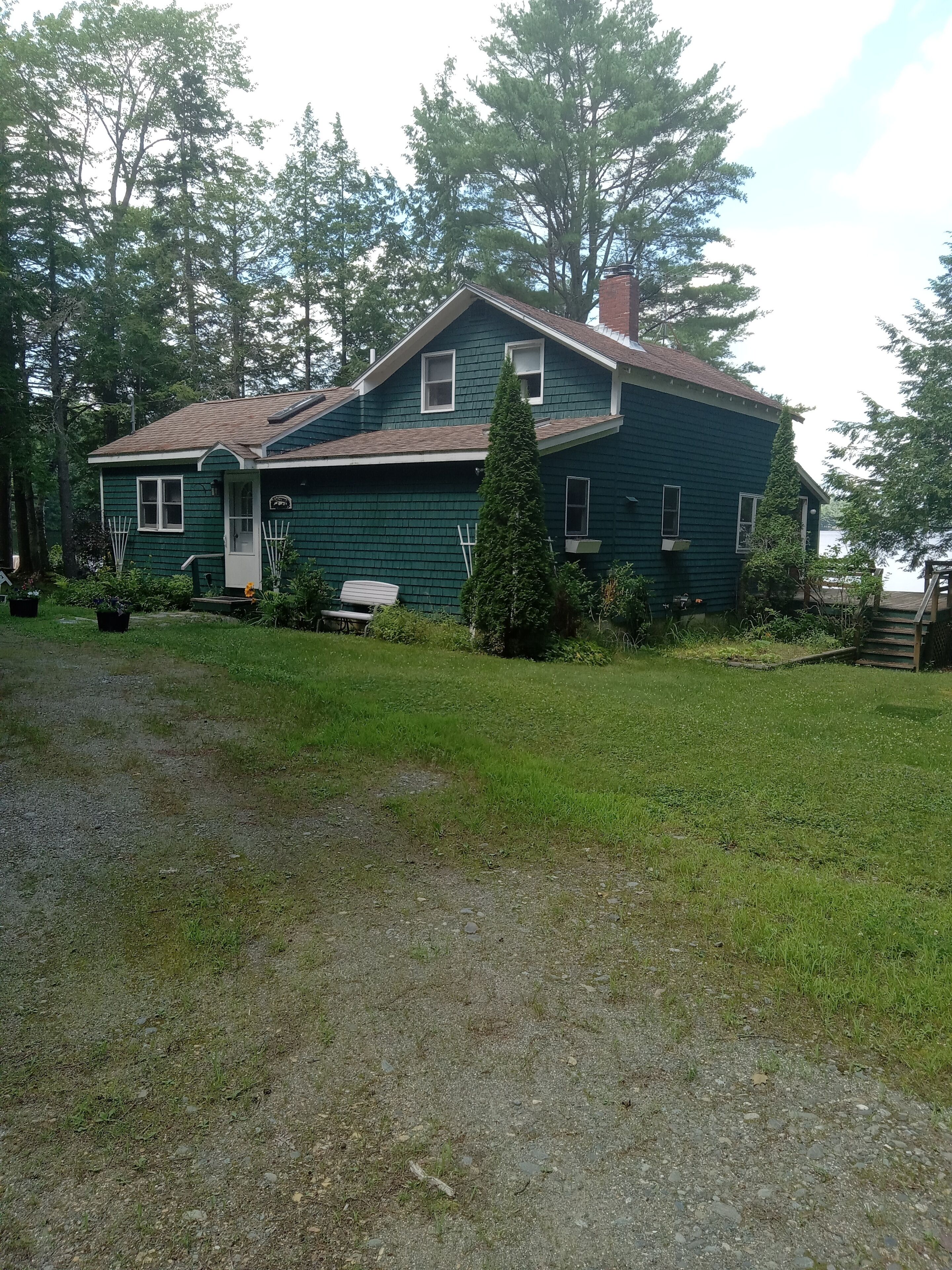 A two-story house with a green exterior, a front porch, and a small deck.
