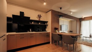 A modern kitchen with wooden cabinets, a dining area with a table and chairs, and a large window with curtains. - Nest Inn Magic Apartment Scala Center (Cluj-Napoca)