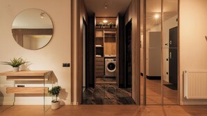 A modern interior with a wooden desk, a mirror, and a laundry area with a washing machine. - Nest Inn Magic Apartment Scala Center (Cluj-Napoca)
