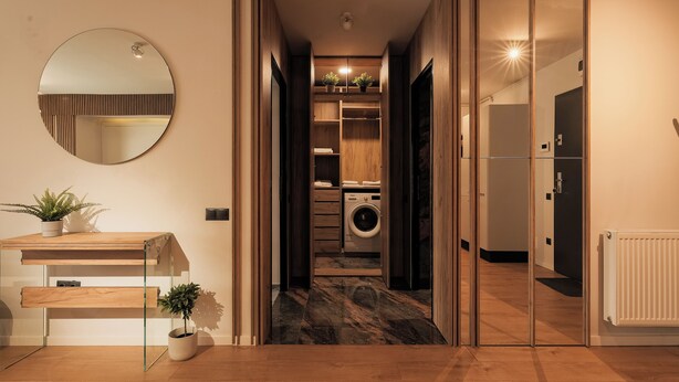 A modern interior with a wooden desk, a mirror, and a laundry area with a washing machine. - Nest Inn Magic Apartment Scala Center (Cluj-Napoca)