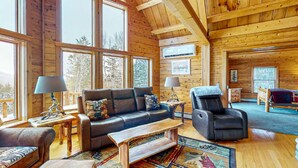 A log cabin interior with a large window, a sofa, a recliner, and a wooden coffee table. - *Lake/Mtn View*Hot Tub*Firepace*Game Room* (Greenville)