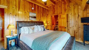 A wooden-paneled bedroom with a bed, nightstand, lamp, and a television. - *Lake/Mtn View*Hot Tub*Firepace*Game Room* (Greenville)