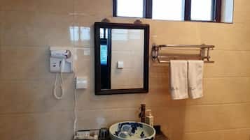 A bathroom with a mirror, a towel rack with towels, a bowl, and a phone.