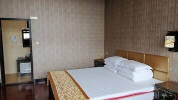 A hotel room with a bed, a bedside table, a mirror, and a wall-mounted telephone.