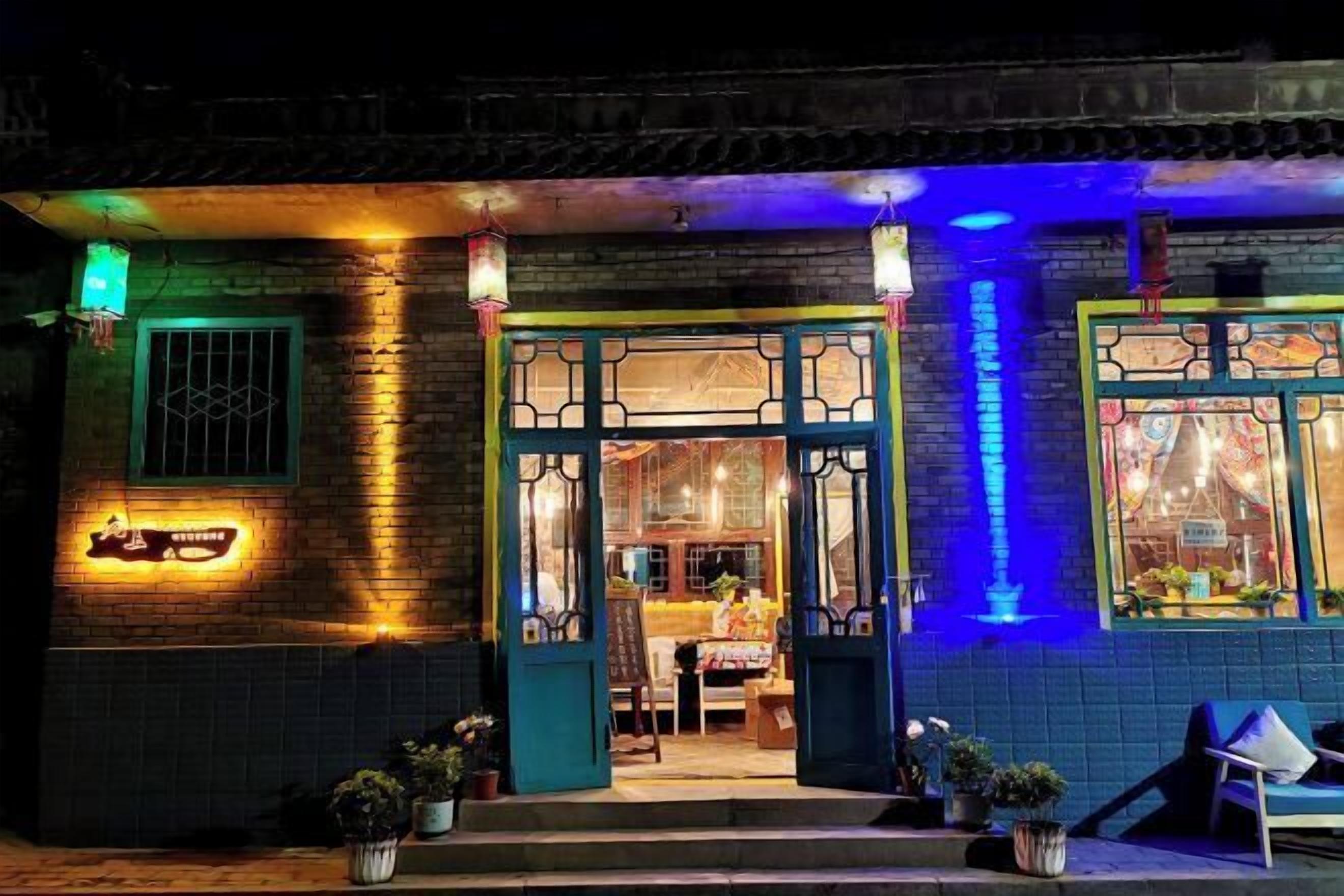 Een traditioneel gebouw met een blauwe gevel, een neonreclame en een blauw verlichte ingang.