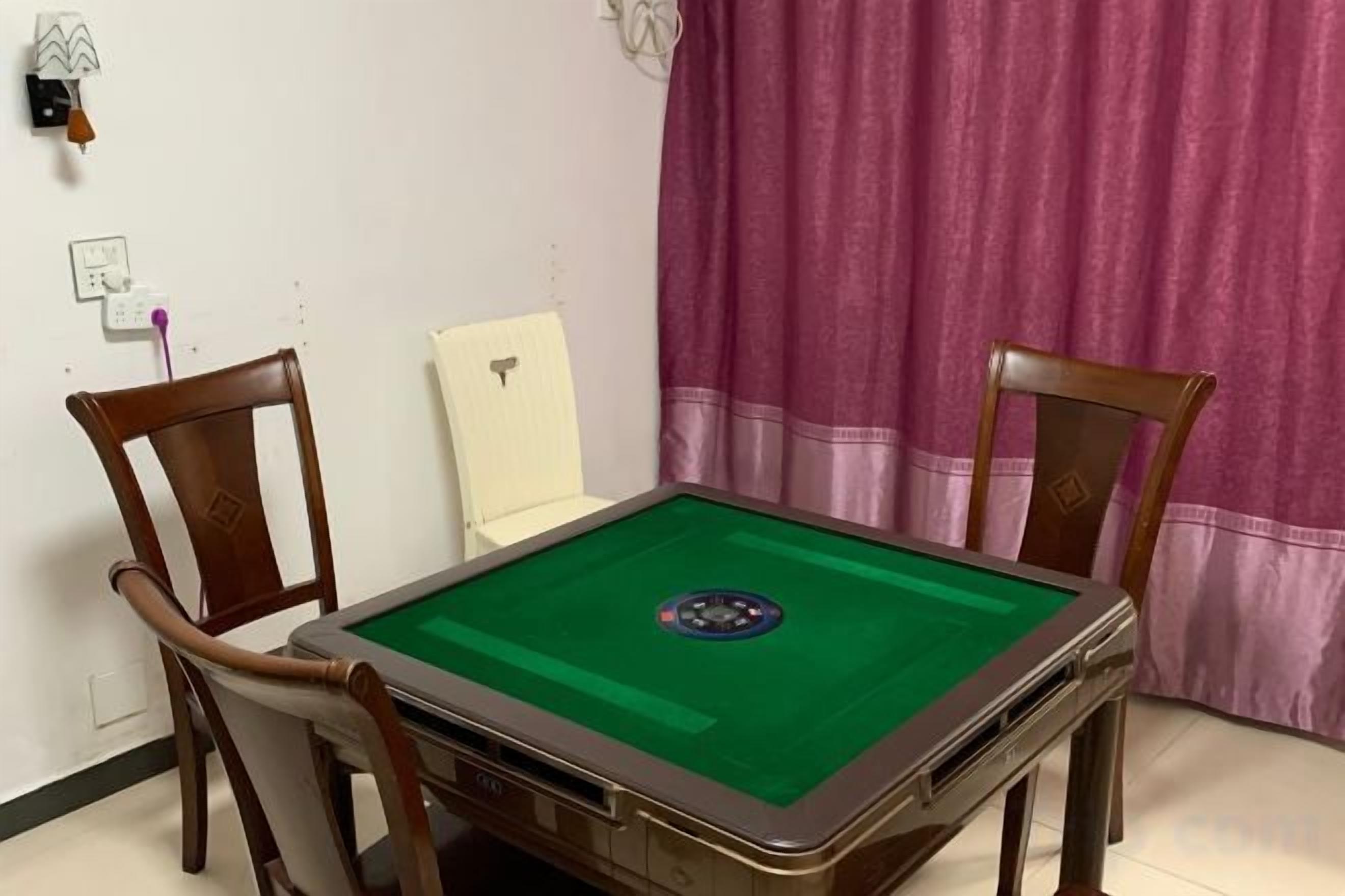Una mesa de billar con cuatro sillas, una silla blanca y una cortina morada al fondo.