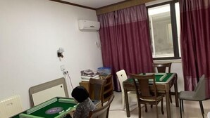 A room with a green felt table for playing mahjong, wooden chairs, a window with purple curtains, and an air conditioning unit on the wall. - lingfeng63 (Yueqing)