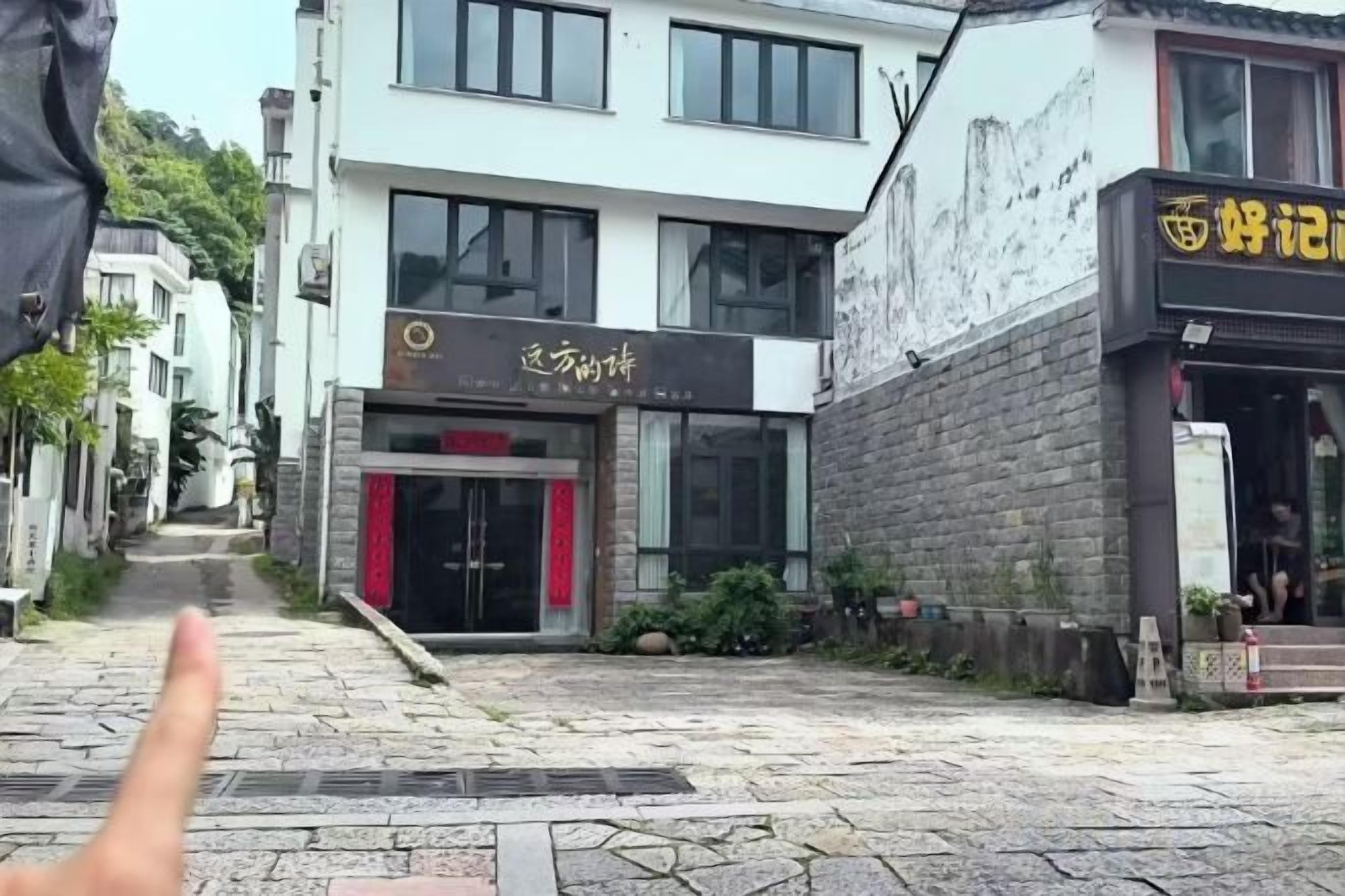 Una calle con edificios, una tienda con toldo rojo y un letrero con caracteres chinos.