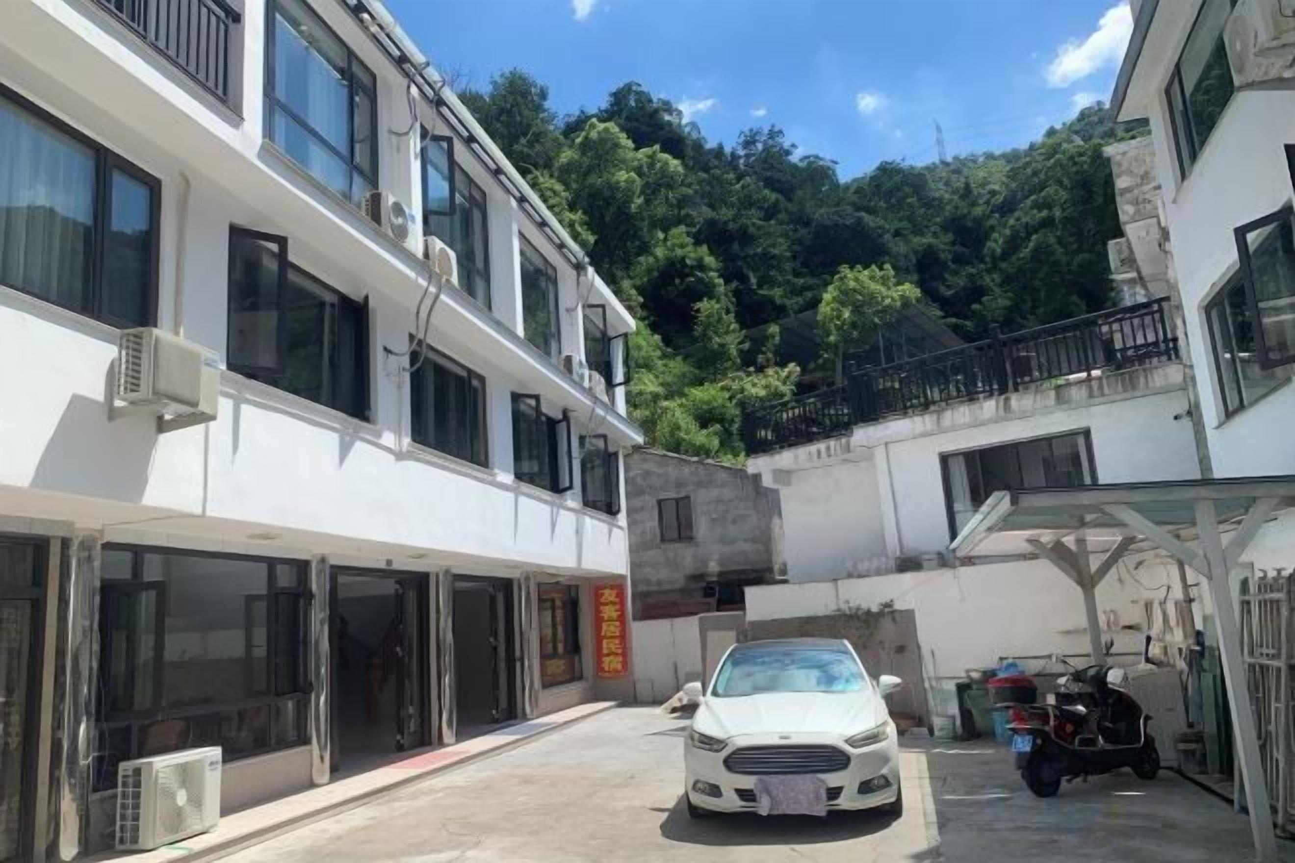 Un edificio de varios pisos, una zona de estacionamiento techada y un automóvil en primer plano.