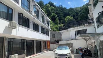 Un edificio de varios pisos, una zona de estacionamiento techada y un automóvil en primer plano.