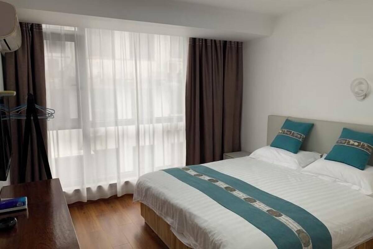 A hotel room with a bed, curtains, a desk, and a chair.