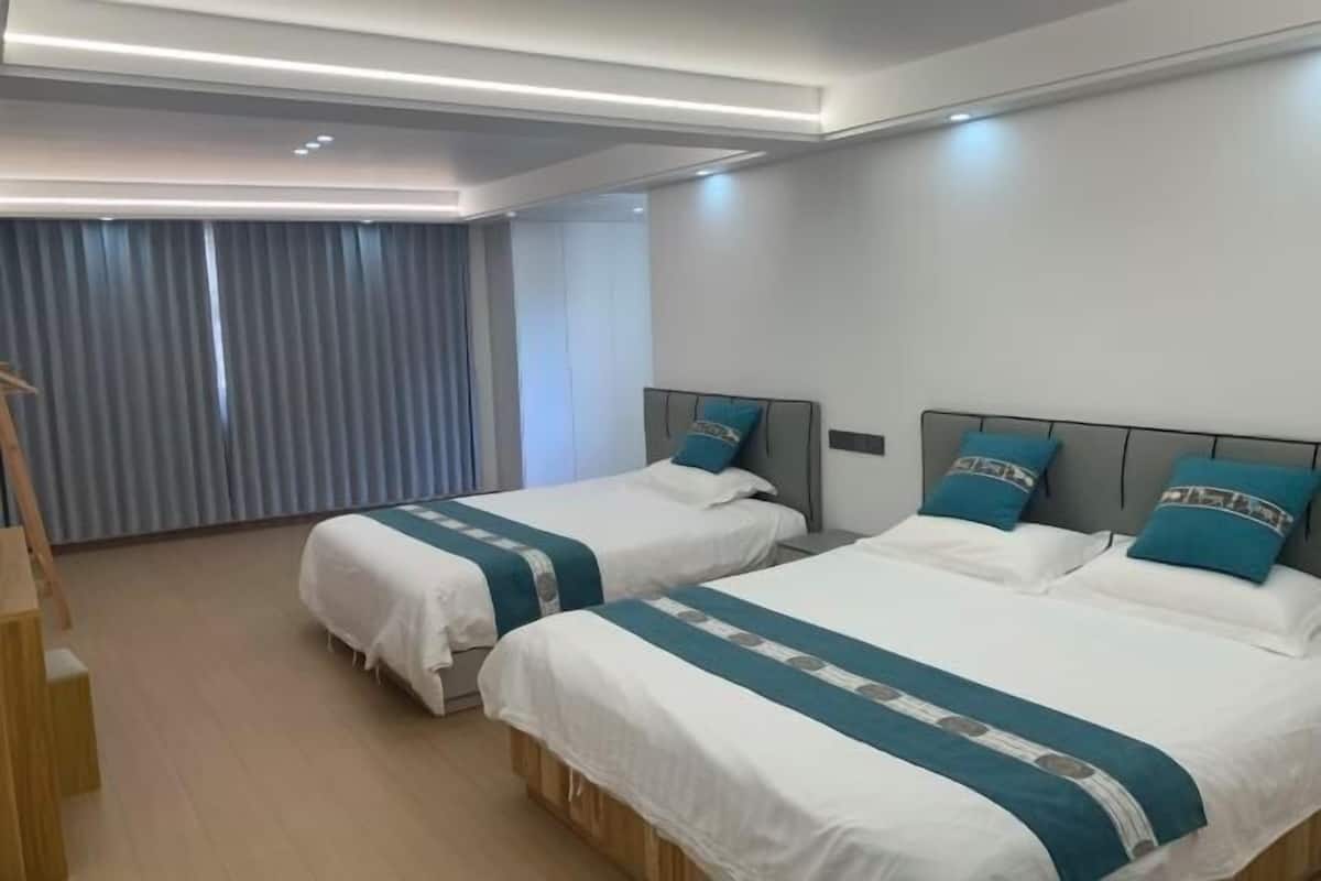 A hotel room with two beds, a wooden desk, and a window with curtains.