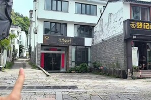 Eine Straße mit Gebäuden, darunter ein Restaurant mit rotem Markisenvorbau und einem Schild mit chinesischen Schriftzeichen.