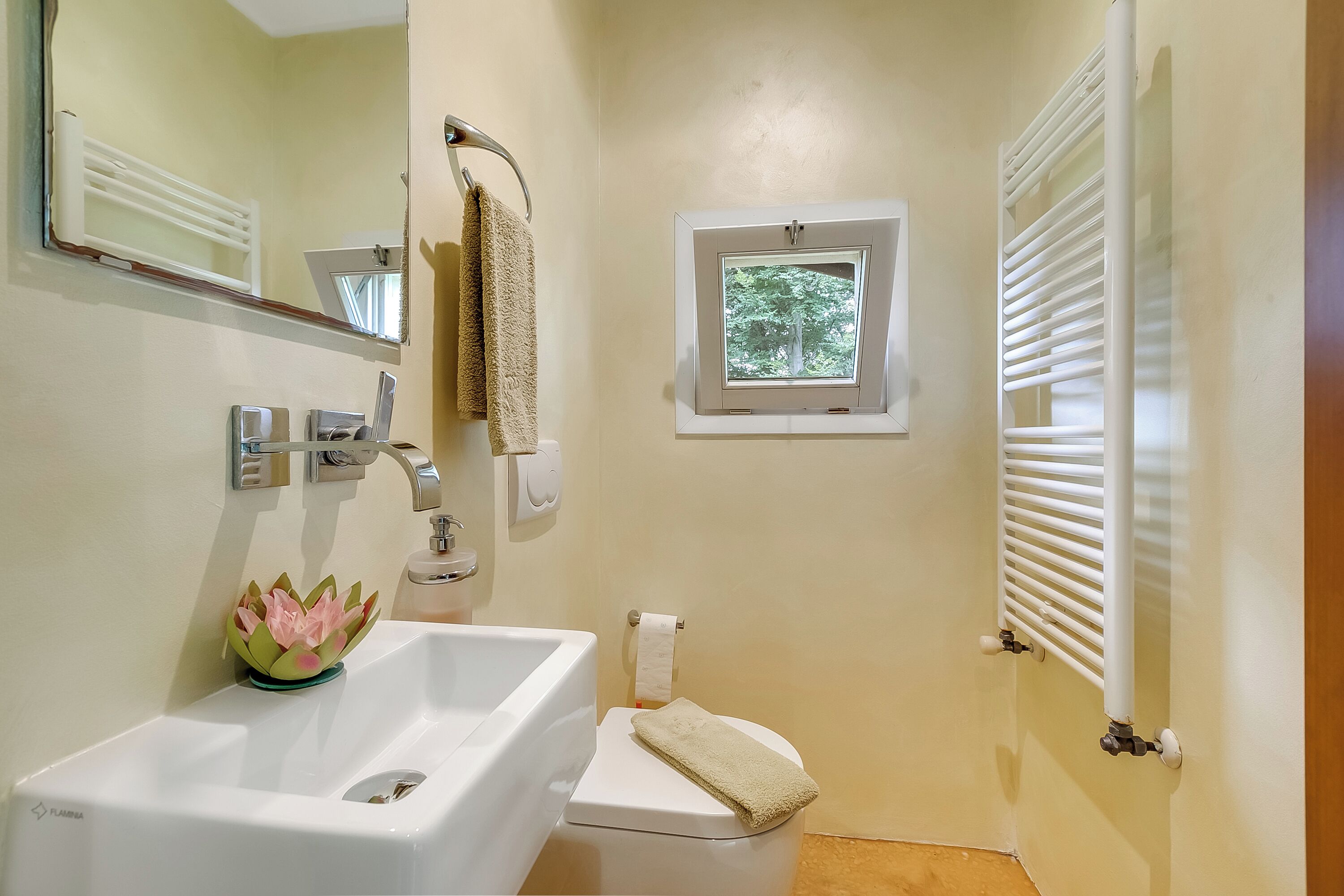 Ein Badezimmer mit Waschbecken, Toilette, Fenster und Handtuchhalter.