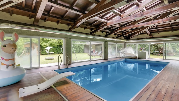 An indoor swimming pool with wooden beams, a slide, and a large inflatable rabbit decoration. - Il Gioiellino Pool And Sauna (Gignese)