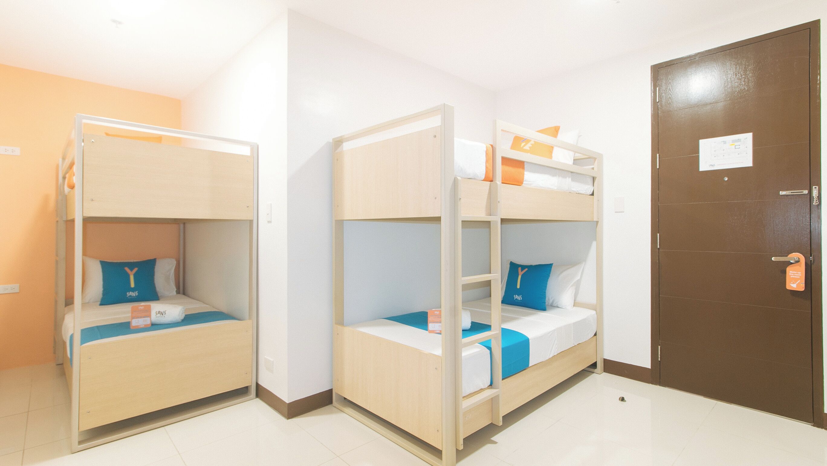 A room with two bunk beds, a brown door, and a white wall.